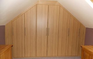 a beautiful wardrobe with hinged doors installed in a sloping loft space