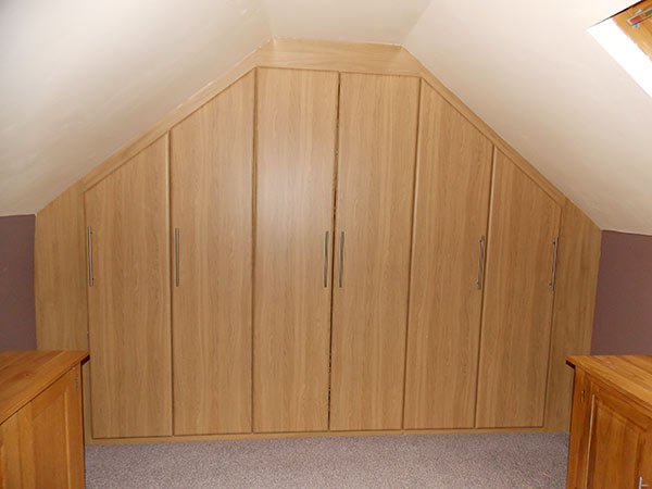a beautiful wardrobe with hinged doors installed in a sloping loft space