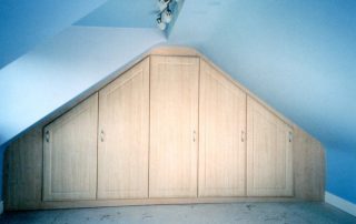 ash hinged wardrobe custom fitted in a loftspace with two sloping roof sections