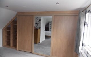 Floor to ceiling sliding wardrobe with mirrored door in reduced height sloping end of a loft conversion